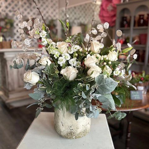 Floral arrangement in a vase on a white table with a blurred indoor background